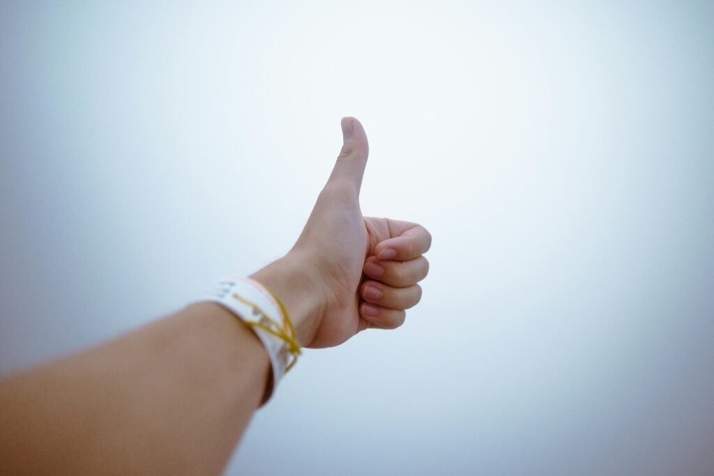A hand giving a thumbs up against a bright sky, representing inner confidence.