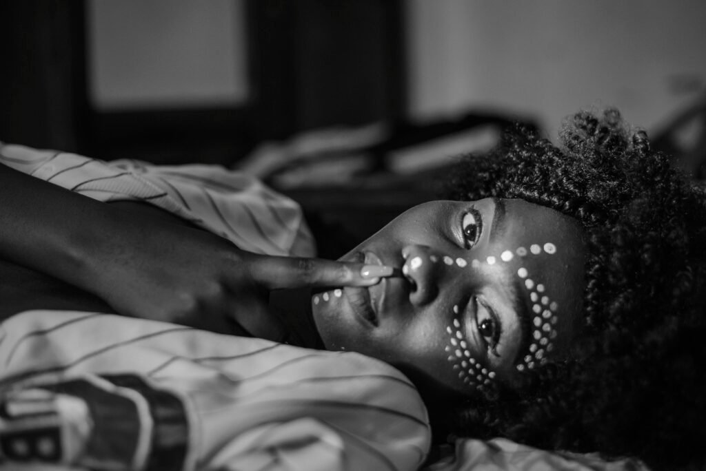 Girl lying on a bed, with her finger on her lips symbolising silence.